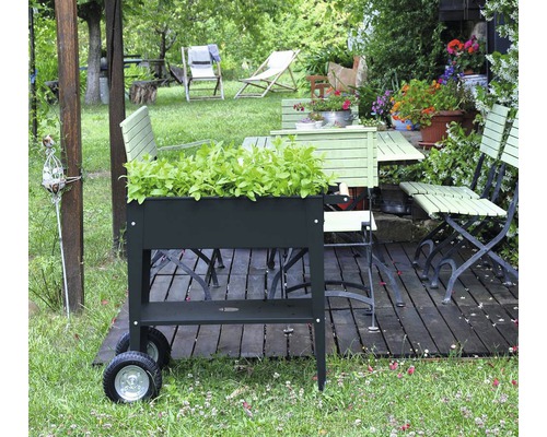 Gartenszene mit Pflanzkasten, Gartentisch und Gartenstühlen auf einer Holzterrasse
