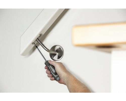 Une personne fixe une rampe à un mur avec un tournevis.