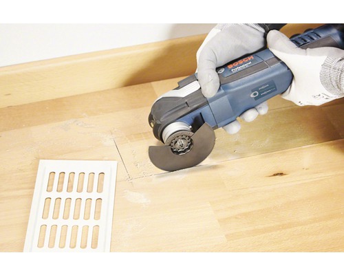 Fraise de sol en cours d''utilisation pour découper un plancher en bois avec une grille de ventilation