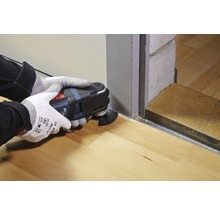 Une personne utilise un outil multifonction pour couper des planchers en bois.