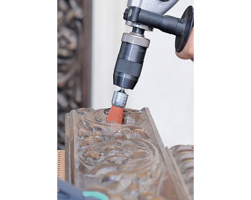 Perceuse avec brosse de nettoyage sur un ornement en bois