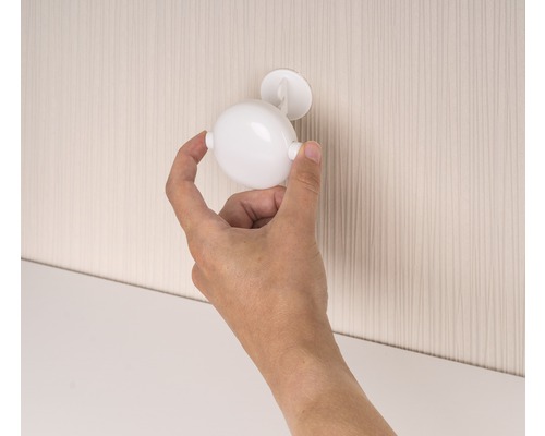 Une main fixe un loquet de meuble sphérique sur une porte d''armoire.