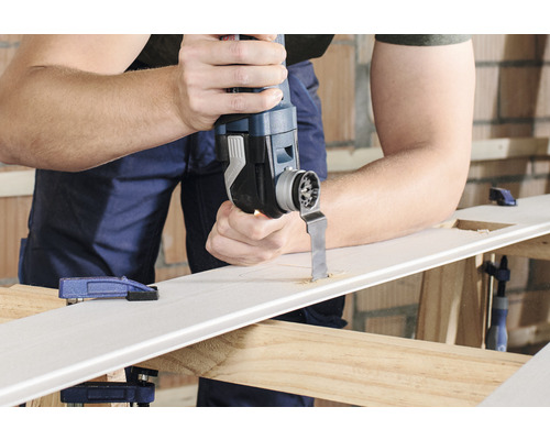 Un homme découpe un trou dans une pièce à l''aide d''un outil multifonction