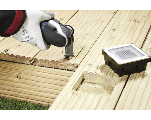 Outil électrique oscillant coupant une terrasse en bois pour un spot de sol encastré