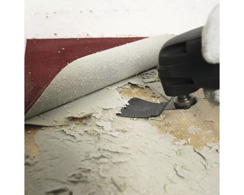 Oszillierendes Multifunktionswerkzeug beim Entfernen von Kleberesten von einem Holzboden