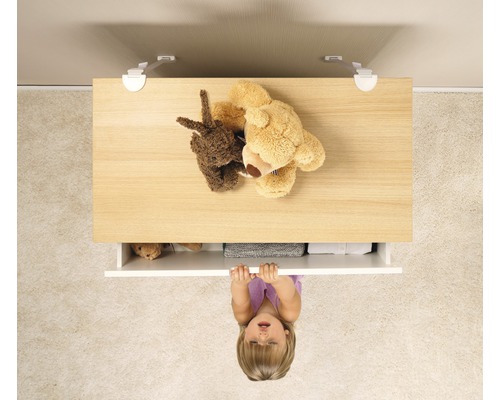Un enfant tire sur une commode avec sécurité enfant, avec des ours en peluche dessus