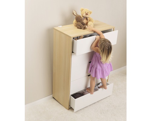 Enfant grimpant sur une commode avec des tiroirs ouverts