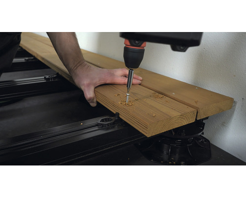 Terrassenbau: Schraube wird in Holzdiele geschraubt