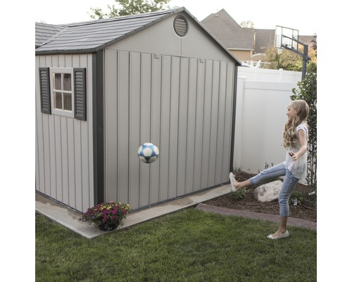 Scène de jardin avec abri de jardin et enfant jouant au football