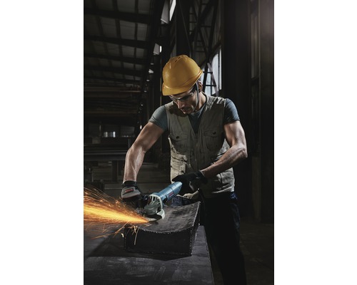 Un ouvrier avec un casque et des lunettes de protection utilise une meuleuse d''angle sur une pièce métallique, ce qui provoque des étincelles.