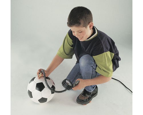 Un enfant gonfle un ballon de foot avec une pompe à ballon.