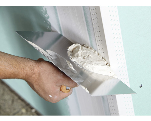 Handwerker trägt Spachtelmasse mit einem Flächenspachtel auf eine Wand auf.