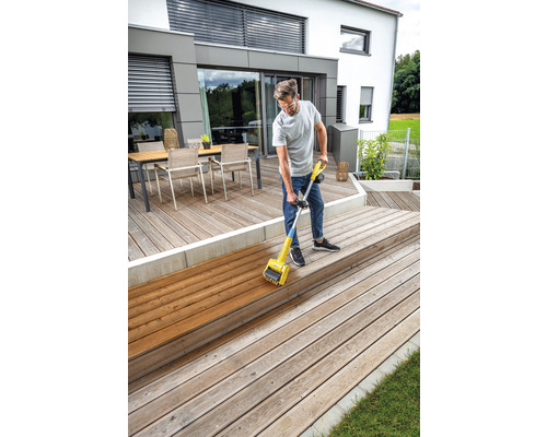 Un homme traite une terrasse en bois avec un appareil à huile pour bois