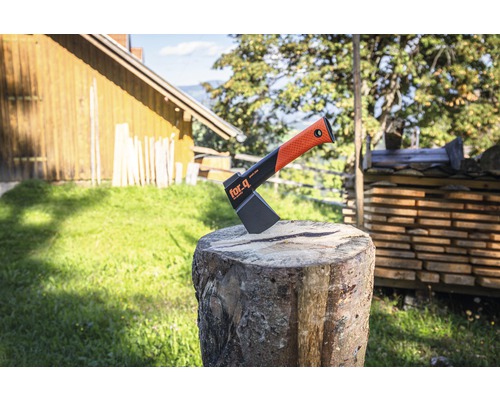 Hache de fendage For_q sur une bûche devant une pile de bois et paysage