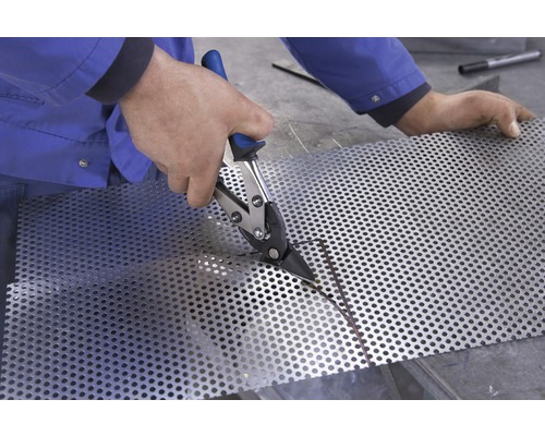 Eine Person schneidet mit einer Blechschere ein Lochblech.