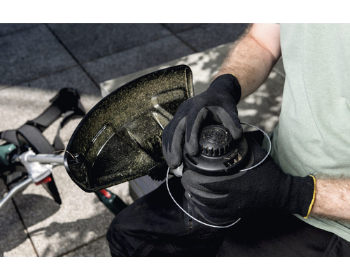 Eine Person wechselt die Spule eines Rasentrimmers aus.