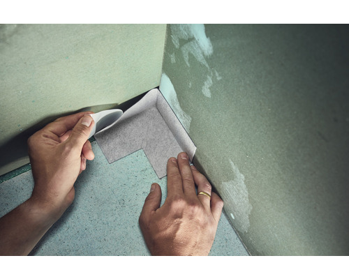 Person verlegt Dichtband in einer Ecke
