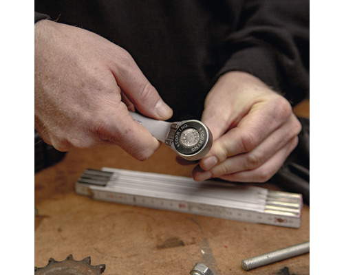 Un homme manipule une clé à cliquet polygonale sur un établi