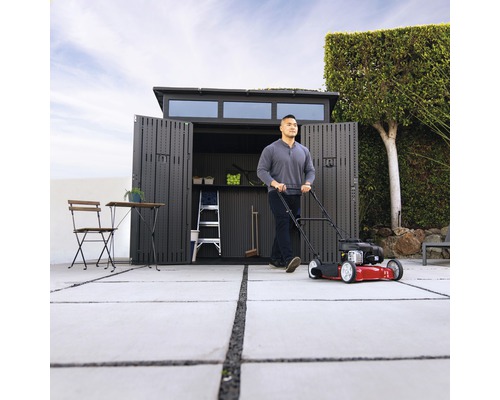 Szene mit Rasenmäher vor offenem Geräteschuppen, Leiter und Gartenmöbeln