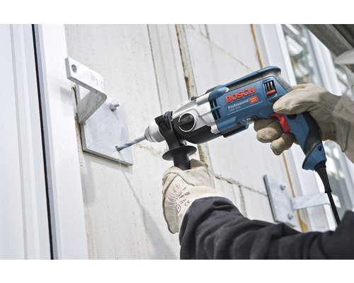Travaux de perçage avec une perceuse à percussion sur un mur avec support