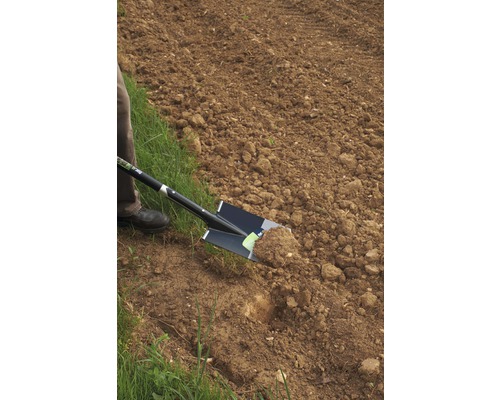 Eine Person gräbt mit einem Spaten in einem Feld.