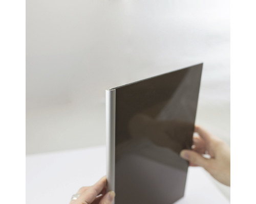Profilé de finition panneau mural douche pour Decodesign rond noir longueur 210 cm Un devant de cuisine sombre avec un bord en aluminium est tenu par des mains.
