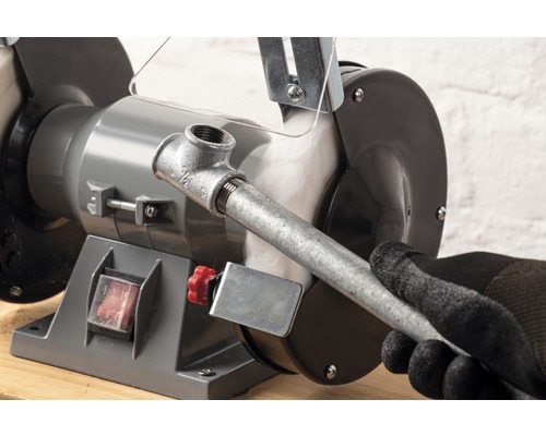 Tischbandschleifer beim Schleifen eines Metallrohrs