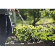 Une personne travaille avec une houe oscillante dans le jardin.