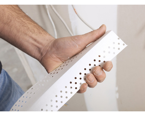 Eine Hand hält ein Eckschutzprofil für Putzarbeiten.