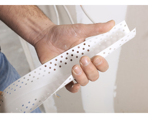 Eine Hand hält ein gelochtes Eckschutzprofil für Trockenbau.