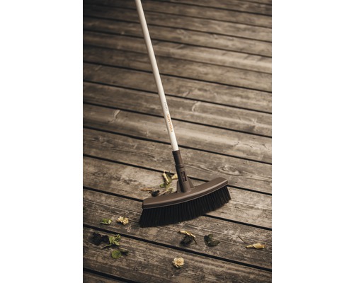 Balai à récurer Fiskars sur terrasse en bois avec des feuilles