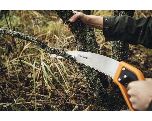 Personne coupant une branche avec une scie à main de Fiskars
