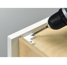 Une visseuse sans fil fixe un connecteur d''angle sur un meuble.