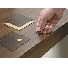 Des autocollants de réparation sont appliqués sur une surface en bois endommagée.