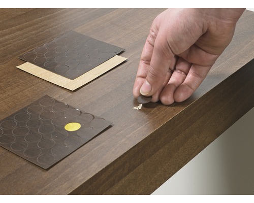 Des autocollants de réparation sont appliqués sur une surface en bois endommagée.
