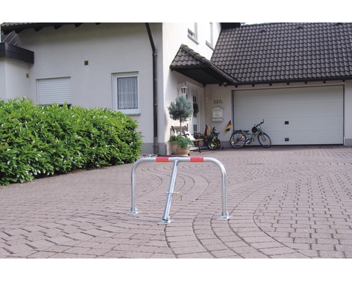 Support à vélos argenté avec marquage rouge devant une maison