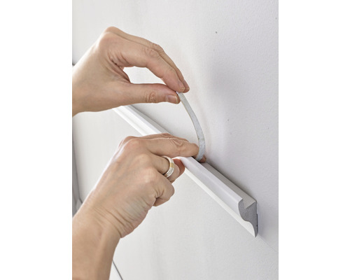 Fixation d''une moulure décorative au mur à l''aide de ruban adhésif