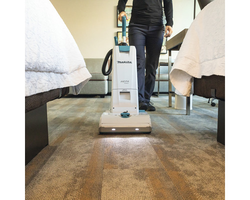 Aspirateur Makita utilisé dans une chambre d''hôtel sur une moquette