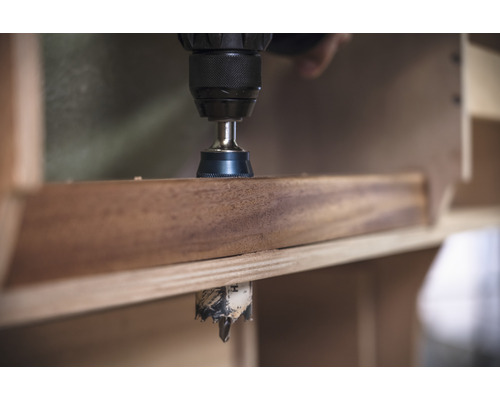 Une perceuse perce un trou dans une planche de bois.