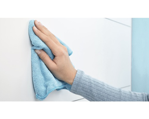 Une main essuie une surface blanche avec un chiffon en microfibres