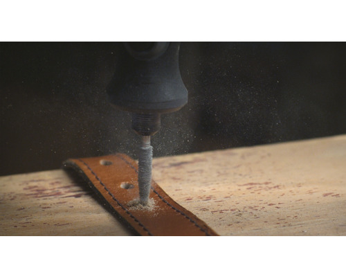 Eine Schleifmaschine bohrt ein Loch in einen Ledergürtel.