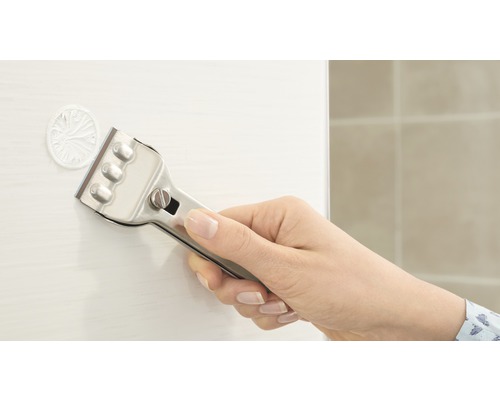 Eine Hand benutzt einen Glasschaber, um Aufkleber zu entfernen.