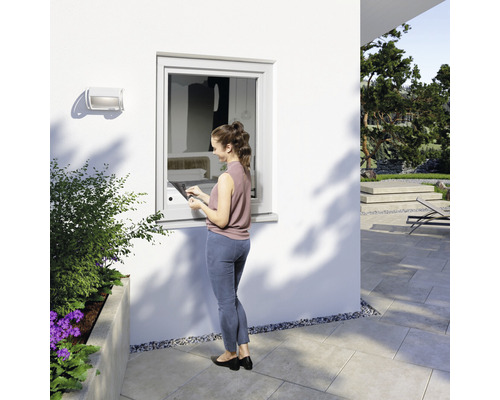 Femme utilisant une tablette pour faire fonctionner une fenêtre à l''extérieur d''une maison.