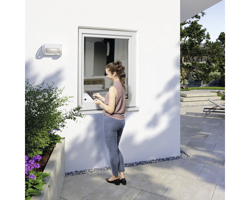 Une femme actionne une fenêtre avec un élément de commande intégré à l''extérieur d''une maison.