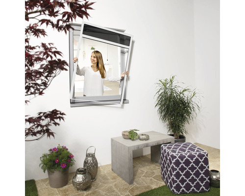 Femme installant une moustiquaire devant une fenêtre