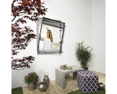 Une femme fixe un écran anti-insectes à la fenêtre à l''extérieur