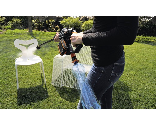 Une personne utilise un nettoyeur haute pression sans fil dans le jardin pour nettoyer une chaise. Une bouteille d''eau est connectée au nettoyeur haute pression.