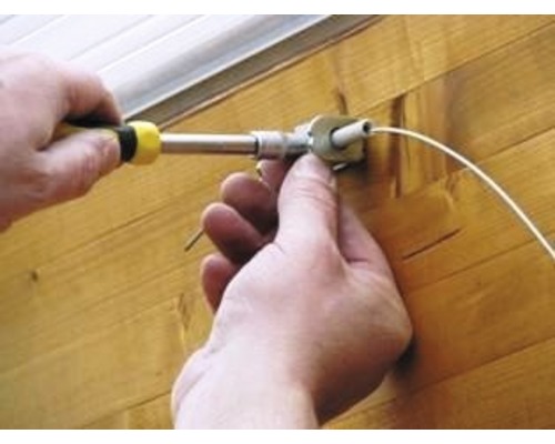 Une personne monte un store avec un tournevis.