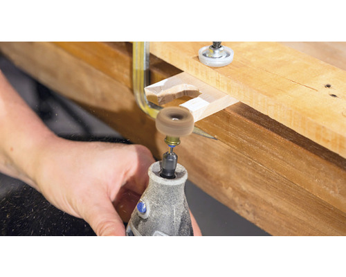 Outil Dremel travaillant une pièce de bois avec une meule abrasive.