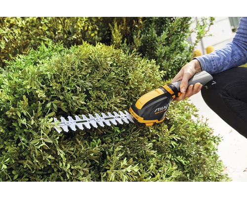 Eine Person schneidet eine Hecke mit einer Stiga Akku-Heckenschere.
